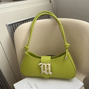 Minimalist avocado green baguette bag with metal logo detail on a white chair