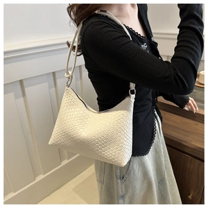 Close-up of white woven leather underarm bag with decorative knot detail on the strap