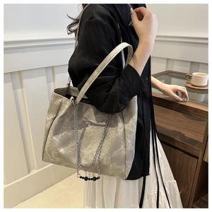 Detail of grey marbled texture leather tote bag with silver chain and bead accents