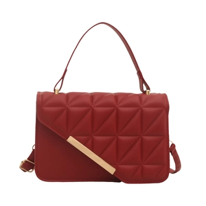 Modern red quilted handbag with gold metal bar accent and adjustable crossbody strap