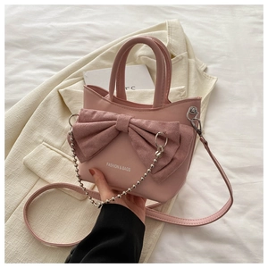 Detail of pink bow handbag with silver bead chain and fashion text on textured leather