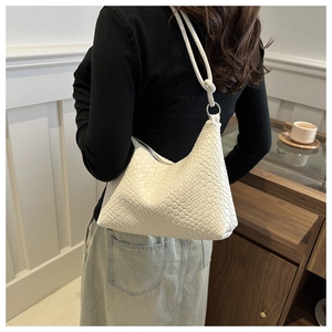 Detail of white woven texture shoulder bag worn by model in a minimalist indoor setting