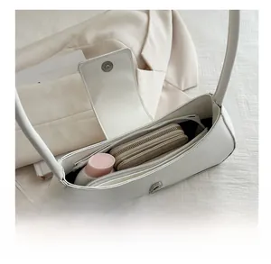 Vista dall'alto dell'interno di una borsa a tracolla bianca con spazio per cosmetici e portafoglio