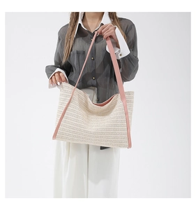 Detail of beige straw tote bag with pink leather shoulder straps and woven texture