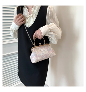 Dettaglio borsa vintage in tessuto jacquard con cornice dorata e tracolla a catena