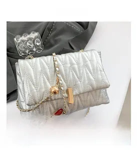 Detail of silver pleated chain bag with gold rectangular lock and quilted texture