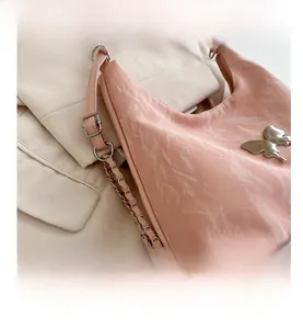 Détail du sac seau rose avec texture froissée brillante et boucle papillon argentée
