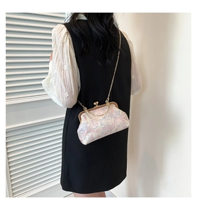 Detailed view of vintage jacquard fabric and golden chain on a mini crossbody bag
