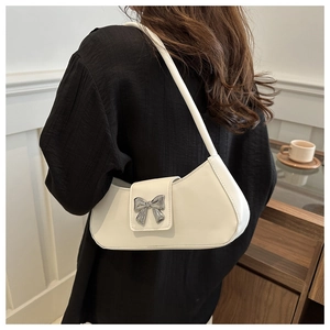 Detail of white underarm bag with a silver metal bow buckle on textured synthetic leather