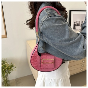 Detail of pink croc-embossed crescent shoulder bag with vintage gold buckle shown on shoulder