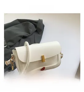 Close-up of white PU crossbody bag featuring a golden rectangular clasp and chain strap