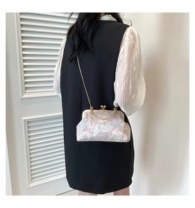 Detail of vintage floral qipao bag with gold metal frame and chain on black vest