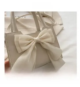 Close-up of creamy white matte PU leather handbag featuring a large chiffon bow detail