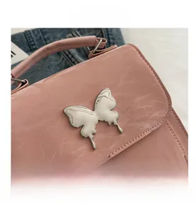 Close-up of pink embossed PU leather surface with silver butterfly metal ornament detail