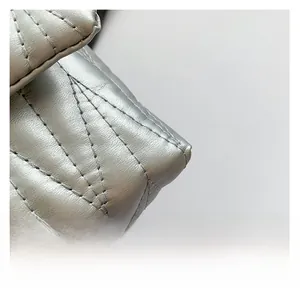 Detail of silver quilted leather texture with V-shaped stitching on a chain shoulder bag
