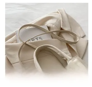 Close-up of minimalist off-white handbag featuring a large silk bow and gold hardware