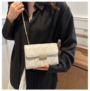 Détail du sac matelassé crème avec fermoir doré et bandoulière chaîne sur un mannequin