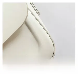 Close-up of premium lychee grain leather texture and clean stitching on a creamy white bag
