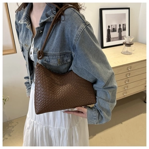 Detail of hand-woven brown leather hobo bag with textured pattern shown on shoulder