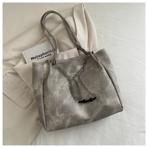 Detail of grey textured leather tote with silver chain and black bead charms