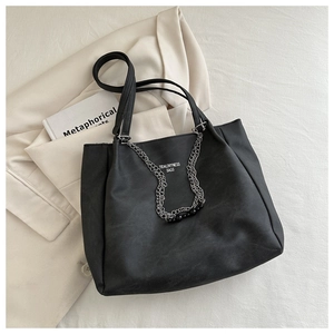 Detail of large black tote bag featuring silver layered chains and round bead accents