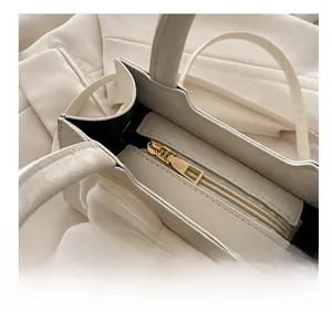 Close-up of smooth gold zipper and white ribbon bow on an elegant minimalist handbag