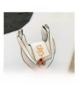 Detail of white crescent bag with gold SS logo, pendant, and black contrast edge