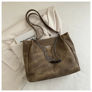 Detail view of vintage brown tote bag with metal chain and black bead pendant decoration
