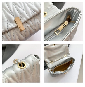 Detail view of silver quilted bag showing gold buckle, zipper pocket and internal space