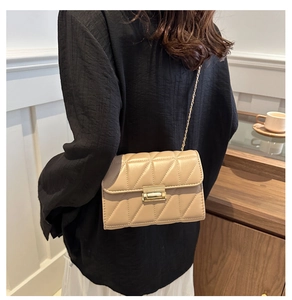 Sac bandoulière beige matelassé avec bandoulière chaîne porté par un mannequin