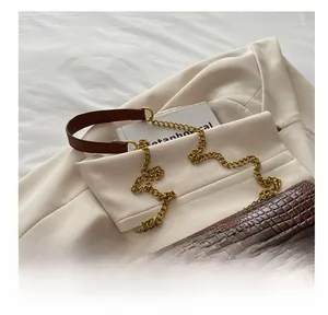 Dettaglio borsa in pelle marrone coccodrillo con logo TB dorato e tracolla a catena