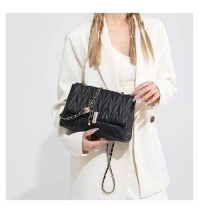Detail of black quilted shoulder bag with gold chain and metal ball clasp detail