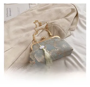 Detailed view of grey silk shell bag with floral embroidery and golden metal handle
