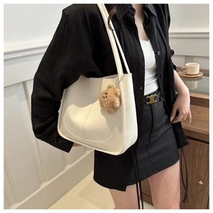 Gros plan du sac cabas en similicuir blanc avec un pendentif d'ours en peluche brun