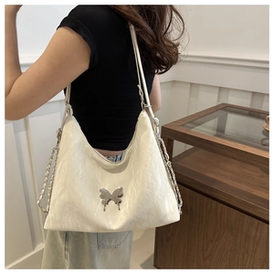 Close-up of white cloud-textured shoulder bag featuring a silver metal butterfly detail