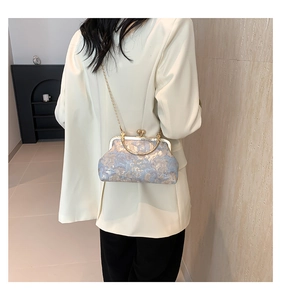 Vista posteriore di una modella con la borsa a telaio in broccato blu e oro con catena