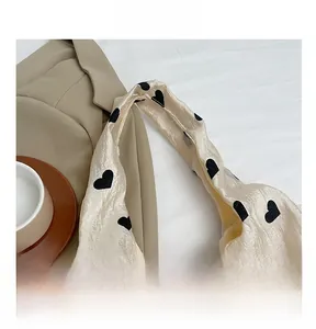 Detailed close-up of cream tote bag fabric with black heart patterns and soft handle