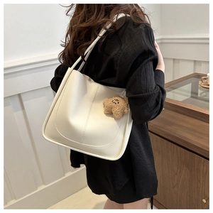 Détail du grand sac seau crème avec coutures verticales et breloque ourson