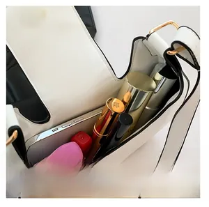 Detail view of the spacious white dumpling bag interior holding a phone and cosmetics