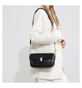 Detail of minimalist black PU leather crossbody bag with golden buckle and chain strap