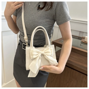 Dettaglio della mini borsa bianca in PU con un grande fiocco di seta e tracolla fine