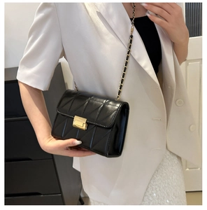 Close-up of black quilted leather crossbody bag with golden clasp and chain strap