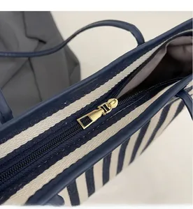 Detail of high-quality golden metal zipper and striped canvas texture of the tote bag