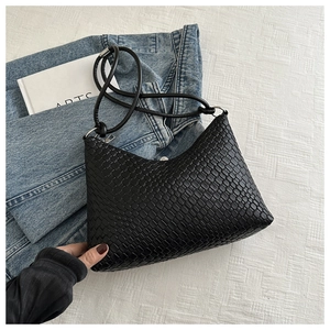 Detail of black woven leather tote bag with checkerboard texture and metal hardware buckle