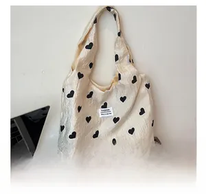 Macro shot of cream heart pattern tote bag featuring a Fashion woven label and wide strap