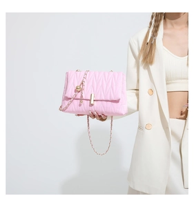 Detail of pink quilted shoulder bag featuring gold chain strap and metal ball charm