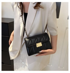Détail d'un sac bandoulière matelassé noir avec boucle dorée porté par un mannequin