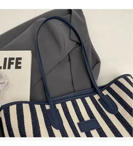 Detail of blue striped canvas tote showing durable leather handles and fabric texture