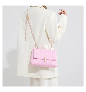Detail of pink quilted PU leather bag featuring gold chain strap and metal clasp on model