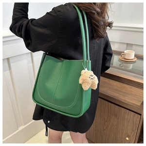 Détail du sac cabas vert en similicuir texturé avec un pendentif ours en peluche